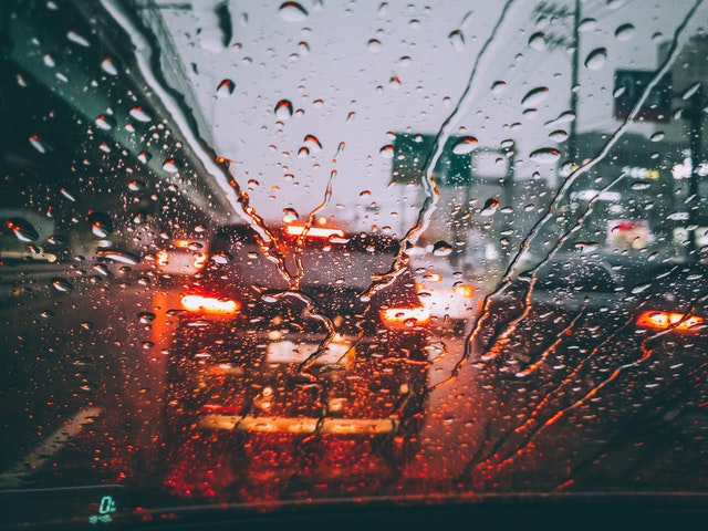 Pohled přes čelní sklo automobilu za deště.